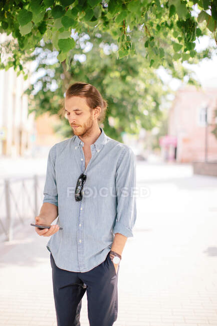 Чоловік стоїть на вулиці і дивиться на свій мобільний телефон (Росія). — стокове фото