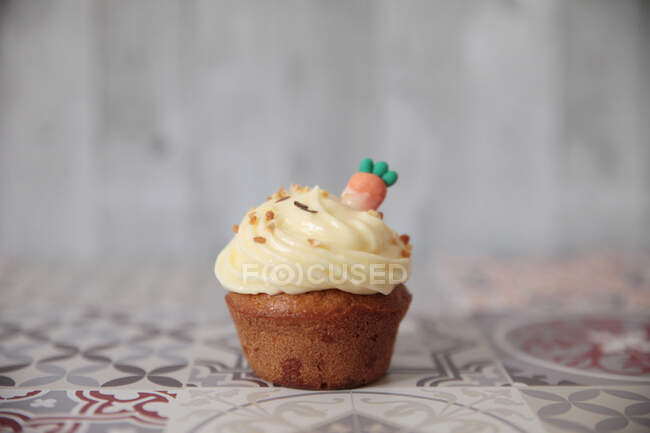 Carrot cupcake with buttercream icing and a carrot decoration — Stock Photo