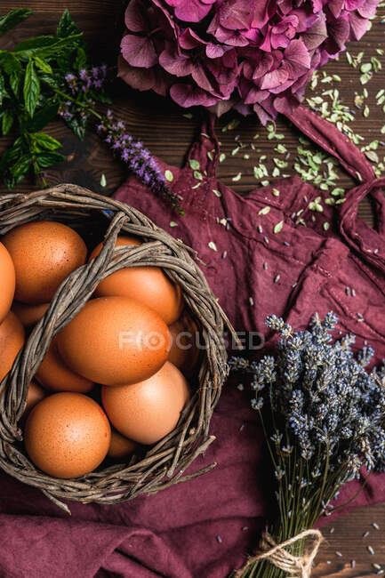 Basked filled with eggs next to flowers — Stock Photo