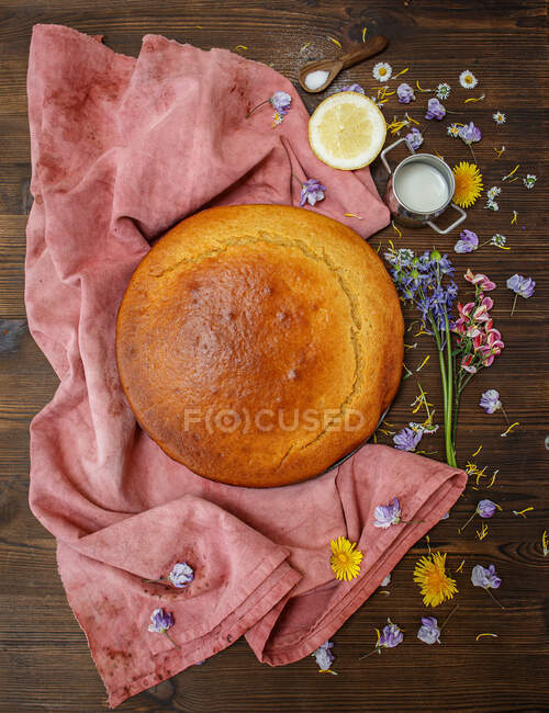 Pétalos de flores junto a un pastel de esponja de limón hecho en casa - foto de stock