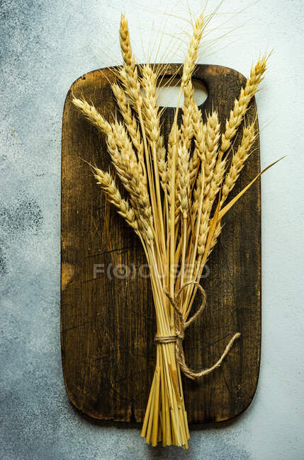 Tesouras amarradas de trigo numa tábua de cortar madeira — Fotografia de Stock