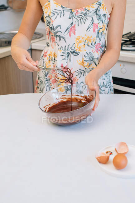 Mujer de pie en cocina batiendo pastel de masa - foto de stock