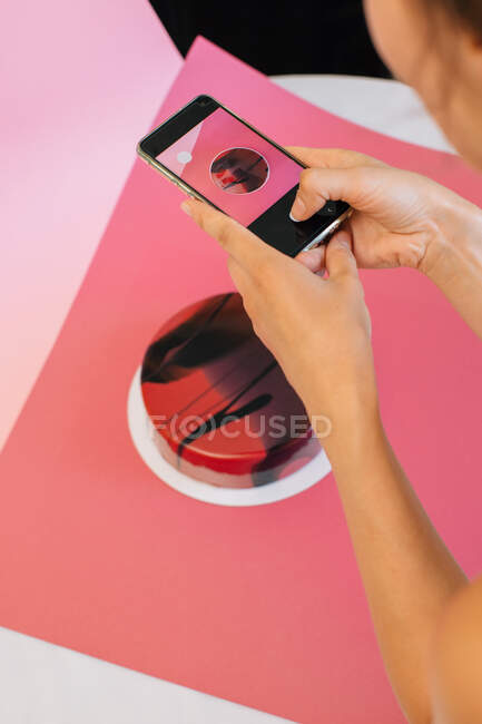 Mujer fotografiando un pastel de terciopelo rojo - foto de stock