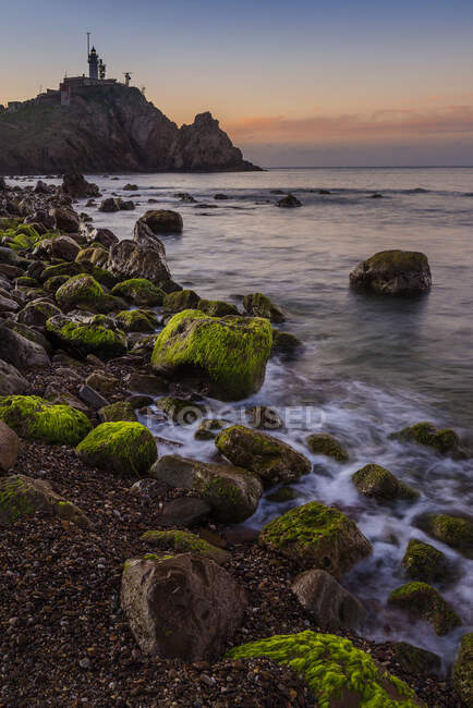 Pôr do sol na enseada de Corralete com o Farol de Cabo de Gata à distância, Almeria, Andaluzia, Espanha, — Fotografia de Stock