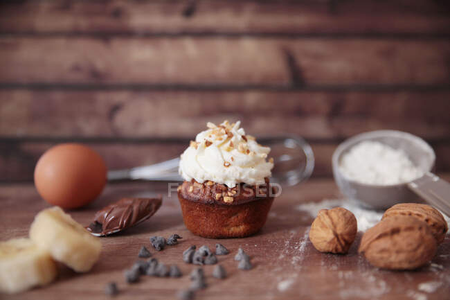 Banana and caramel cupcake with buttercream icing and ingredients — Stock Photo