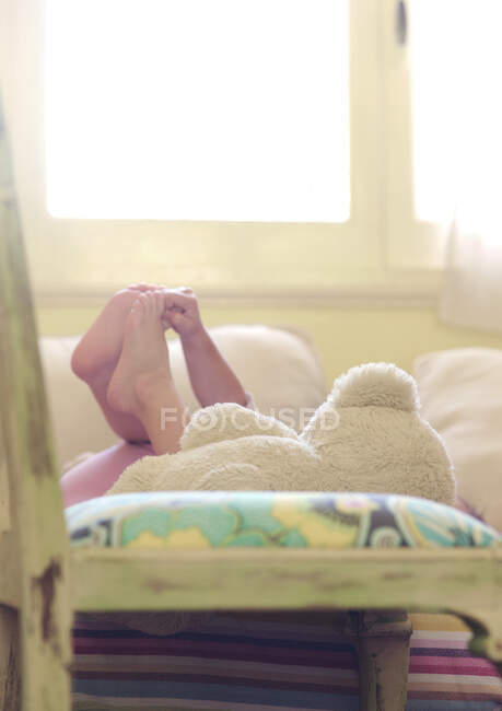 Mädchen liegt auf einem Sofa und spielt mit ihren Füßen — Stockfoto