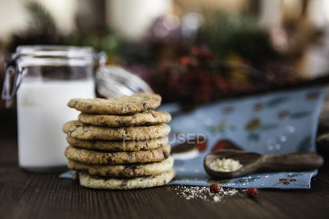 Pila de galletas de chips de chocolate junto a los ingredientes - foto de stock