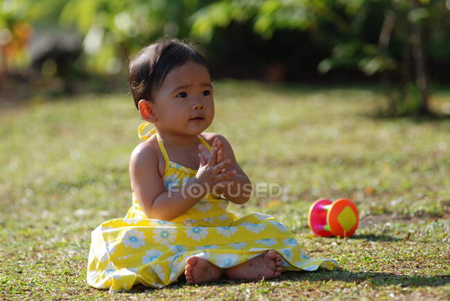 Девушка сидит в парке и играет с игрушками, Индонезия — стоковое фото