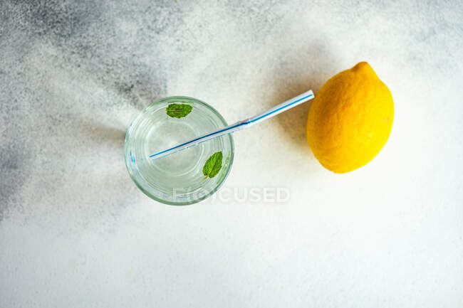 Overhead view of a glass of water with mint leaves and lemon — Stock Photo