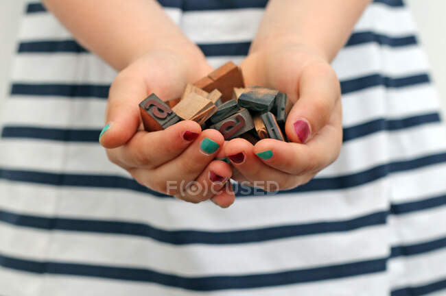 Close-up das mãos de uma menina segurando caracteres tipográficos — Fotografia de Stock