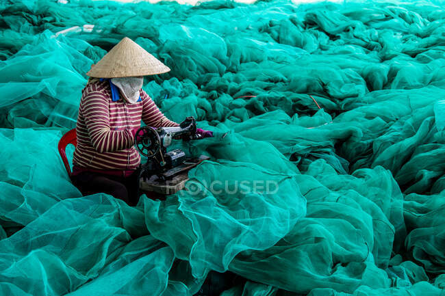 Mujer reparando redes de pesca, Vietnam - foto de stock