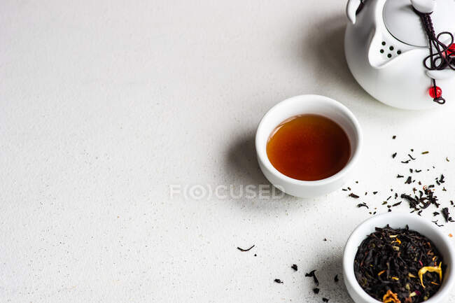 Cup of tea with tea leaves and a tea pot — Stock Photo