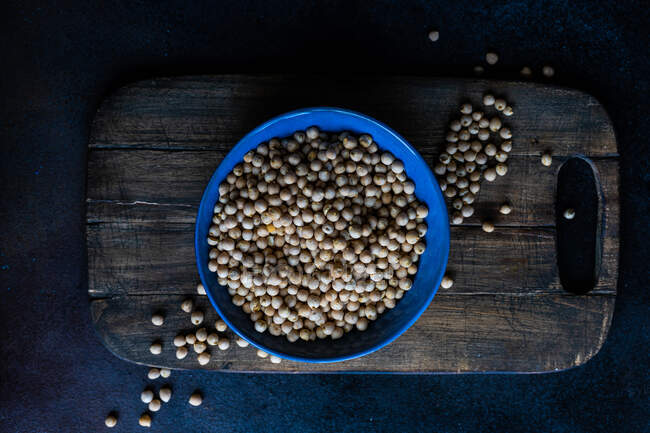 Overhead view of a bowl of chickpeas on a chopping board — Stock Photo