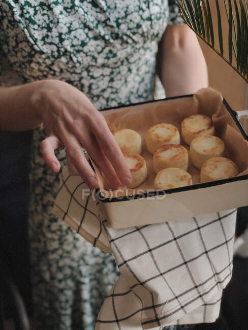 Femme tenant un plat avec des gâteaux au fromage faits maison — Photo de stock