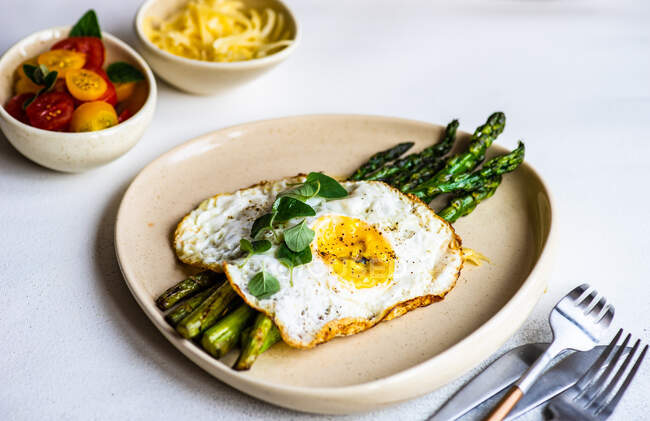 Grilled asparagus with a fried egg, tomato salad and grated cheese — Stock Photo