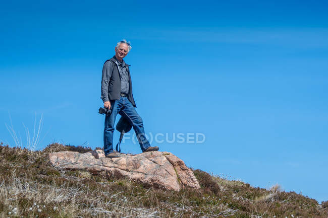 Man standing on a rock holding a camera, Scozia, Regno Unito — Foto stock