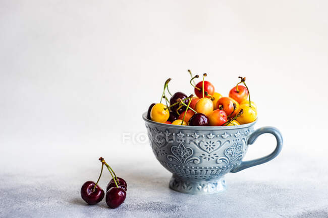 Cup of multi coloured cherries — Stock Photo
