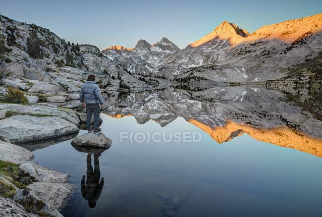 Uomo in piedi su una roccia guardando Mount Hooper Riflessione in Rose Lake, Sierra National Forest, California, Stati Uniti d'America — Foto stock