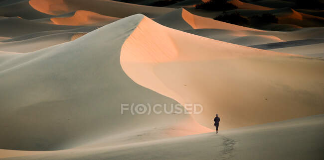 Woman walking in sand dunes, Mesquite Flat Sand Dunes, Death Valley, California, USA — Stock Photo
