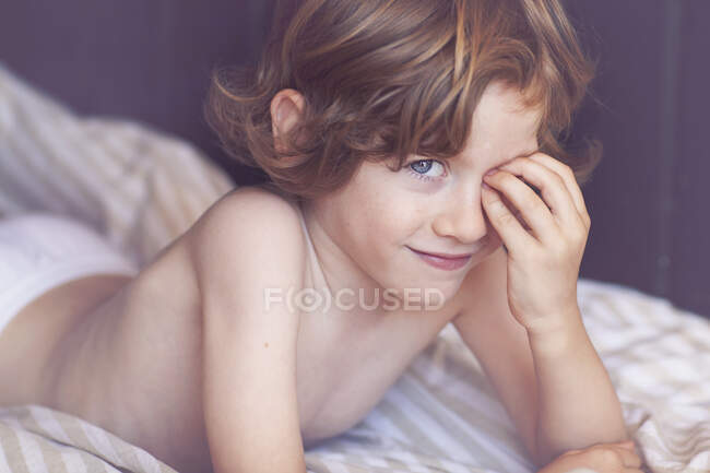 Portrait of a smiling boy lying on a bed — Stock Photo