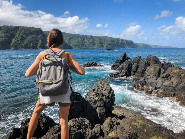 Woman standing on cliffs along Road to Hana looking at view, Maui, Hawaii, EUA — Fotografia de Stock