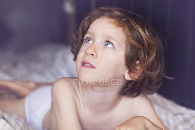 Портрет мальчика, лежащего на кровати и смотрящего вверх — стоковое фото