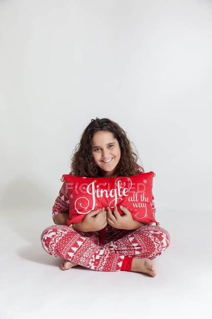 Portrait of a happy girl in pyjamas holding a Christmas pillow — Stock Photo