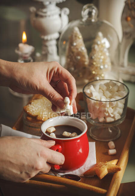 Woman putting marshmallows in a cup of hot chocolate at Christmas — Stock Photo