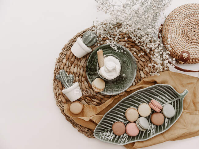 Маккеоны на блюде в форме листьев, цветы, украшения из кактусов и корзинка на белом фоне — стоковое фото