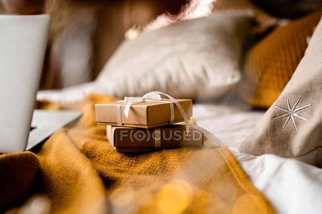 Подарочные коробки на кровати рядом с ноутбуком — стоковое фото