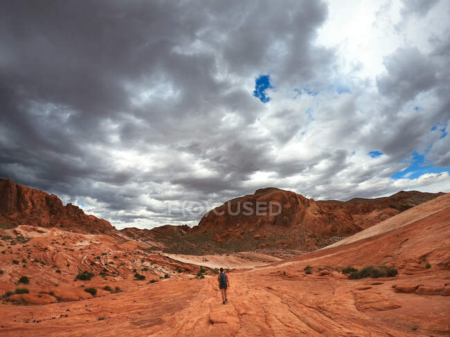 Жінка подорожує по Долині Вогняної Держави з штормом, що наближається, Невада, США. — стокове фото