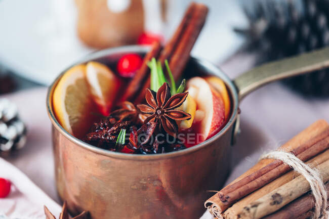 Mulled wine with spices and cinnamon sticks on wooden background — Stock Photo