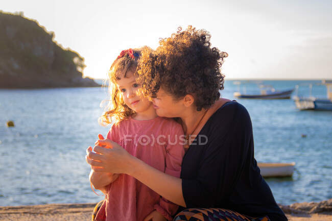 Мать обнимает дочь на пляже, armacao dos buzios, rio de janeiro, brazil — стоковое фото