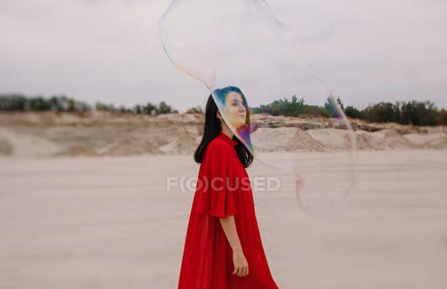 Femme dansant avec une grosse bulle de savon dans le désert — Photo de stock