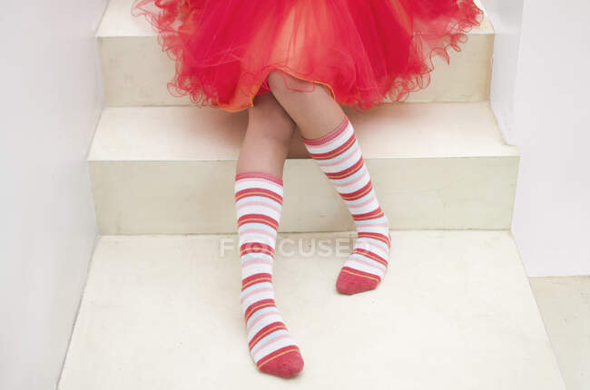 Дівчина-підліток в смугастих шкарпетках сидить на сходах — стокове фото