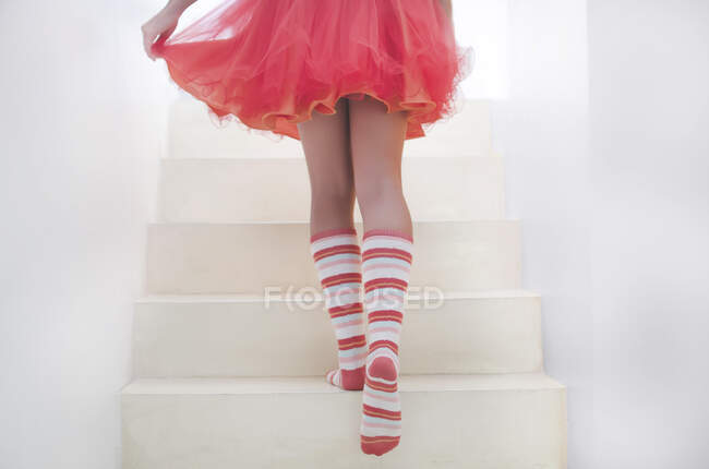 Teenage girl wearing striped socks walking up a staircase — Stock Photo