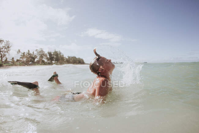 Menino deitado no oceano surfando usando chinelos de mergulho, Havaí, EUA — Fotografia de Stock