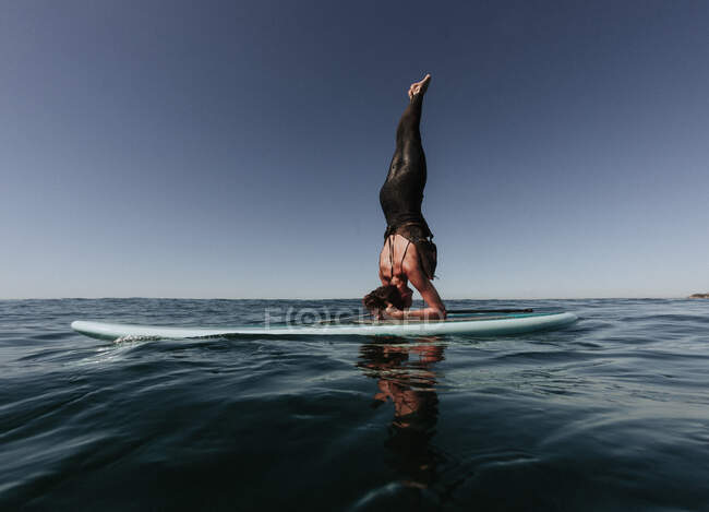 Femme faisant un appui-tête sur une planche à pagaie, Laguna Beach, Californie, États-Unis — Photo de stock