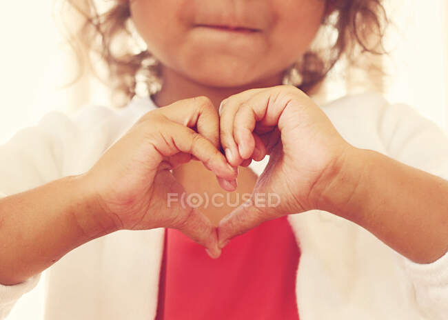 Chica haciendo una forma de corazón con sus manos - foto de stock