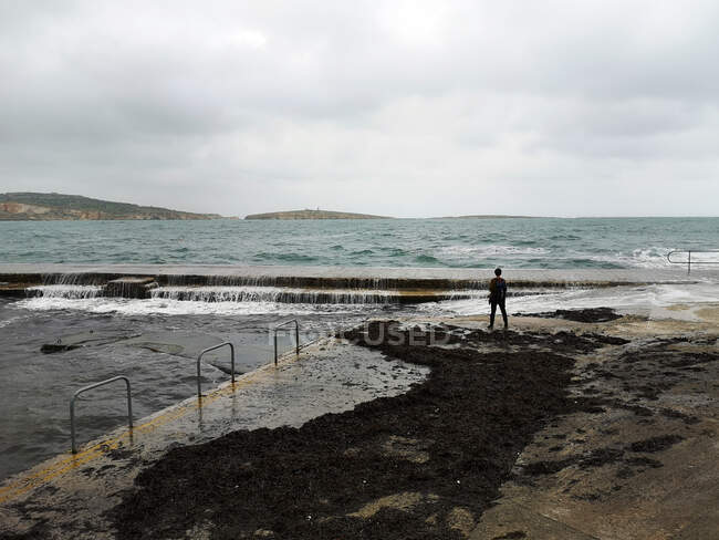 Uomo in piedi sul lungomare affacciato sul mare, St Paul's Bay, Bugibba, Malta — Foto stock