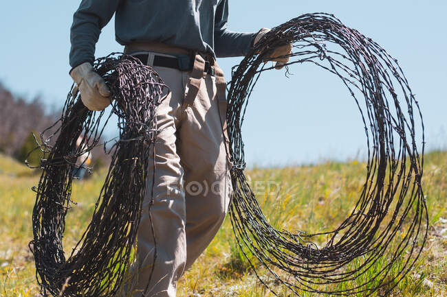 Rancher carrying rolls of barbed wire, USA — Stock Photo