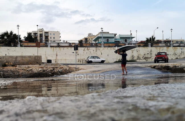 Hombre caminando fuera del mar llevando una tabla de surf en su cabeza, Bugibba, Malta - foto de stock