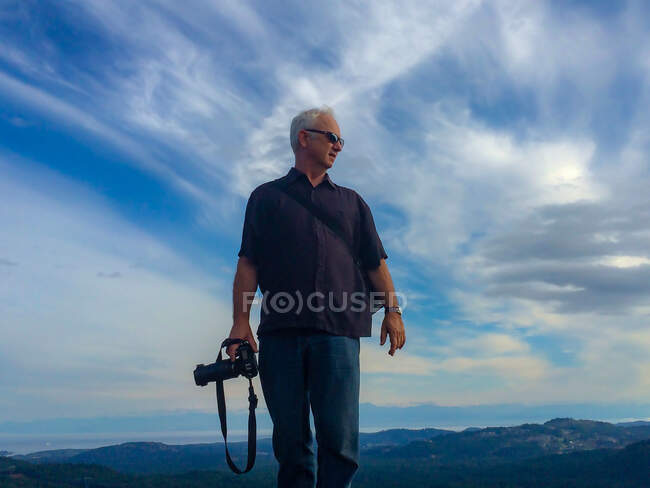 Retrato de un hombre en un paisaje rural sosteniendo una cámara, Canadá - foto de stock