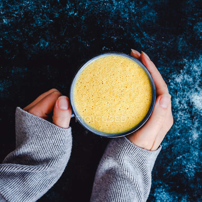 Woman holding a cup of turmeric milk — Stock Photo
