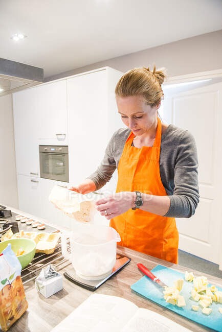 Жінка стоїть на кухні зважуючи борошно — стокове фото