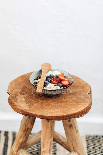 Tigela de muesli com bagas frescas em um banquinho de madeira — Fotografia de Stock