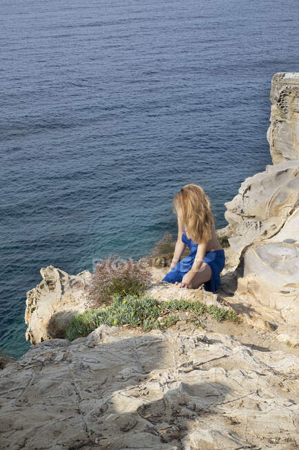 Woman kneeling on rocks by sea, Gulf of Baratti, Tuscany, Italy — Stock Photo