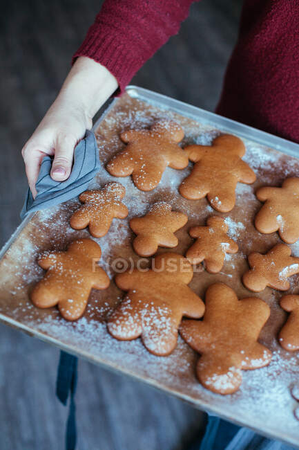 Mulher segurando uma bandeja de cozimento com biscoitos de gengibre — Fotografia de Stock