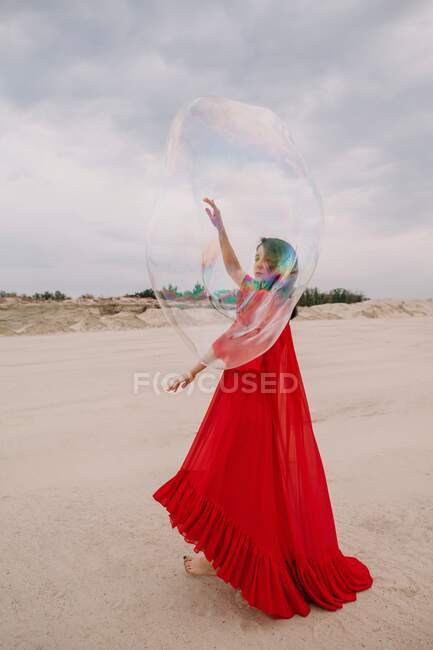 Mulher dançando com grande bolha de sabão no deserto — Fotografia de Stock