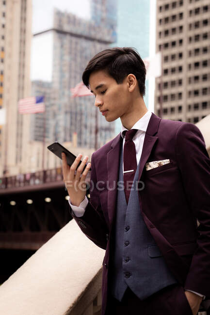 Junger Geschäftsmann, der mit seinem Handy am Flussufer steht, Chicago, Illinois, USA — Stockfoto